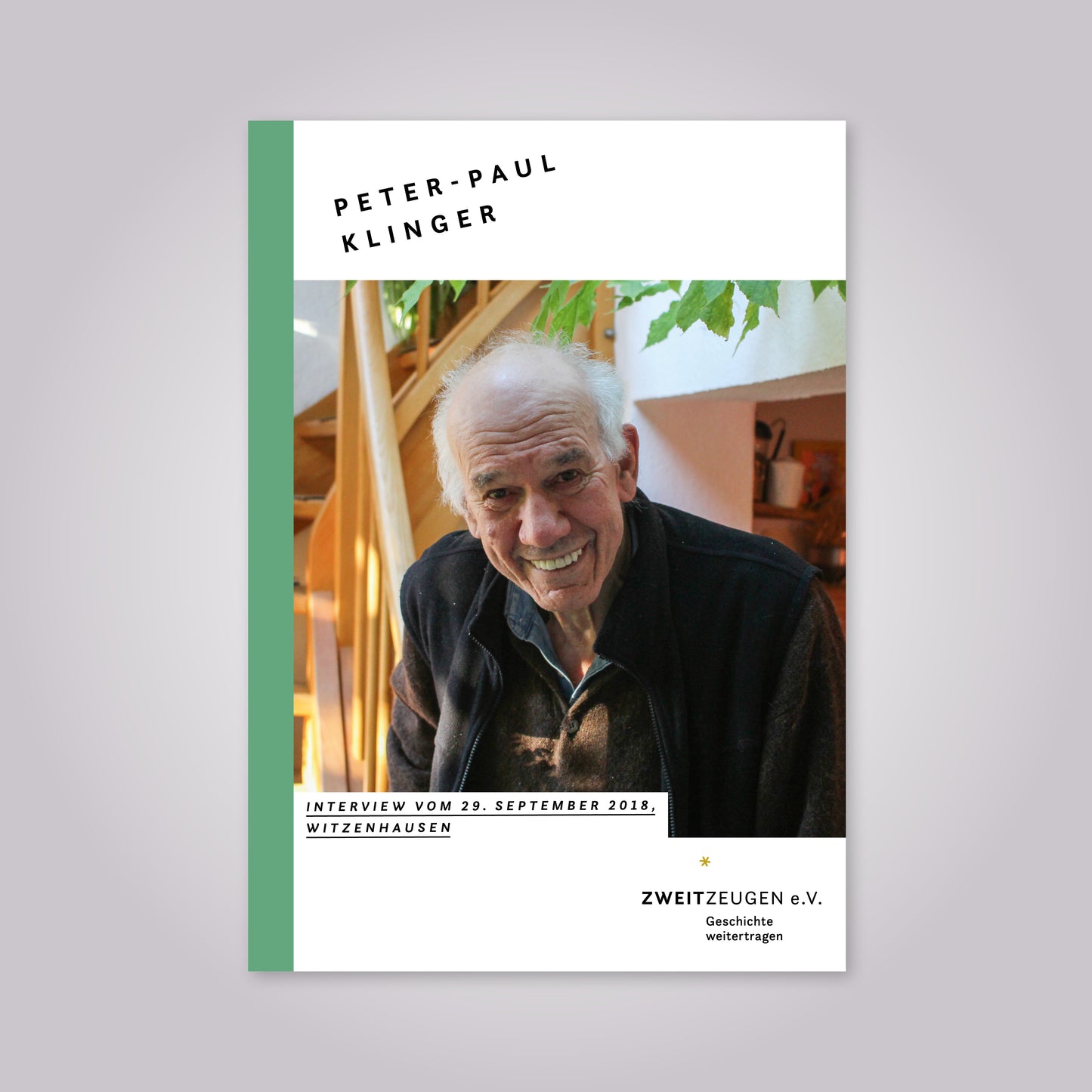 Ein alter Mann mit Halbglaze lächelt in die Kamera. Er trägt ein Hemd, einen Pullover un eine dunkle Weste.