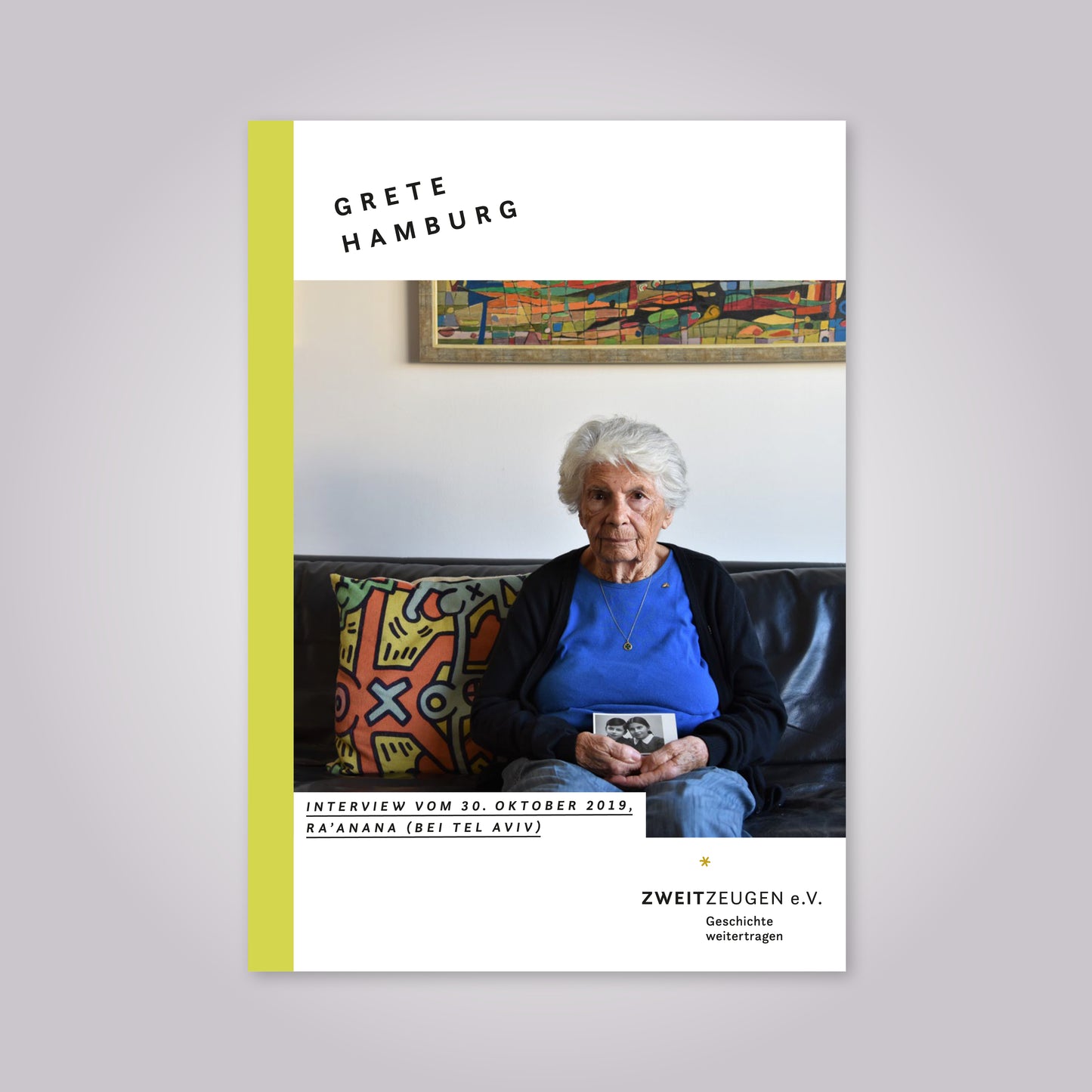 Magazin-Cover: Alte Frau mit weißen Haaren sitzt auf einem Sofa und hält ein Foto in den Händen.